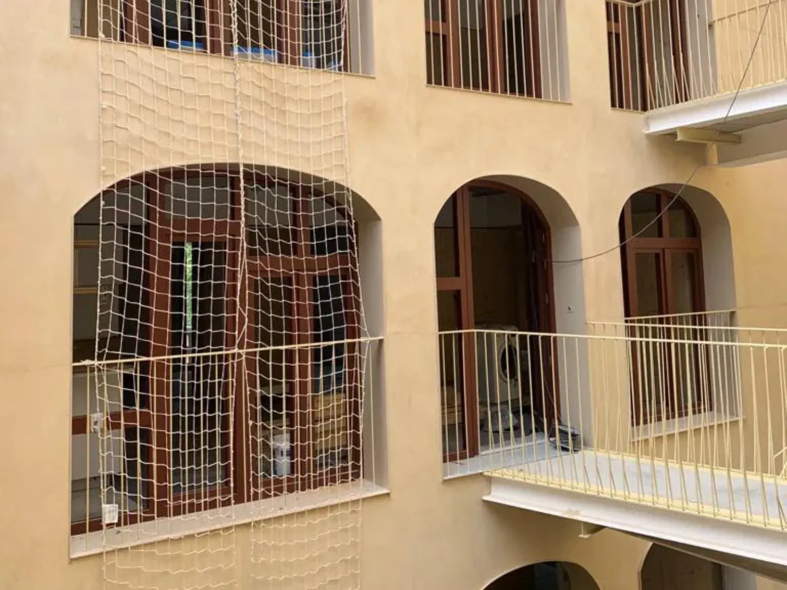 Fachada de edificio con ventanas de madera en arco protegidas con red